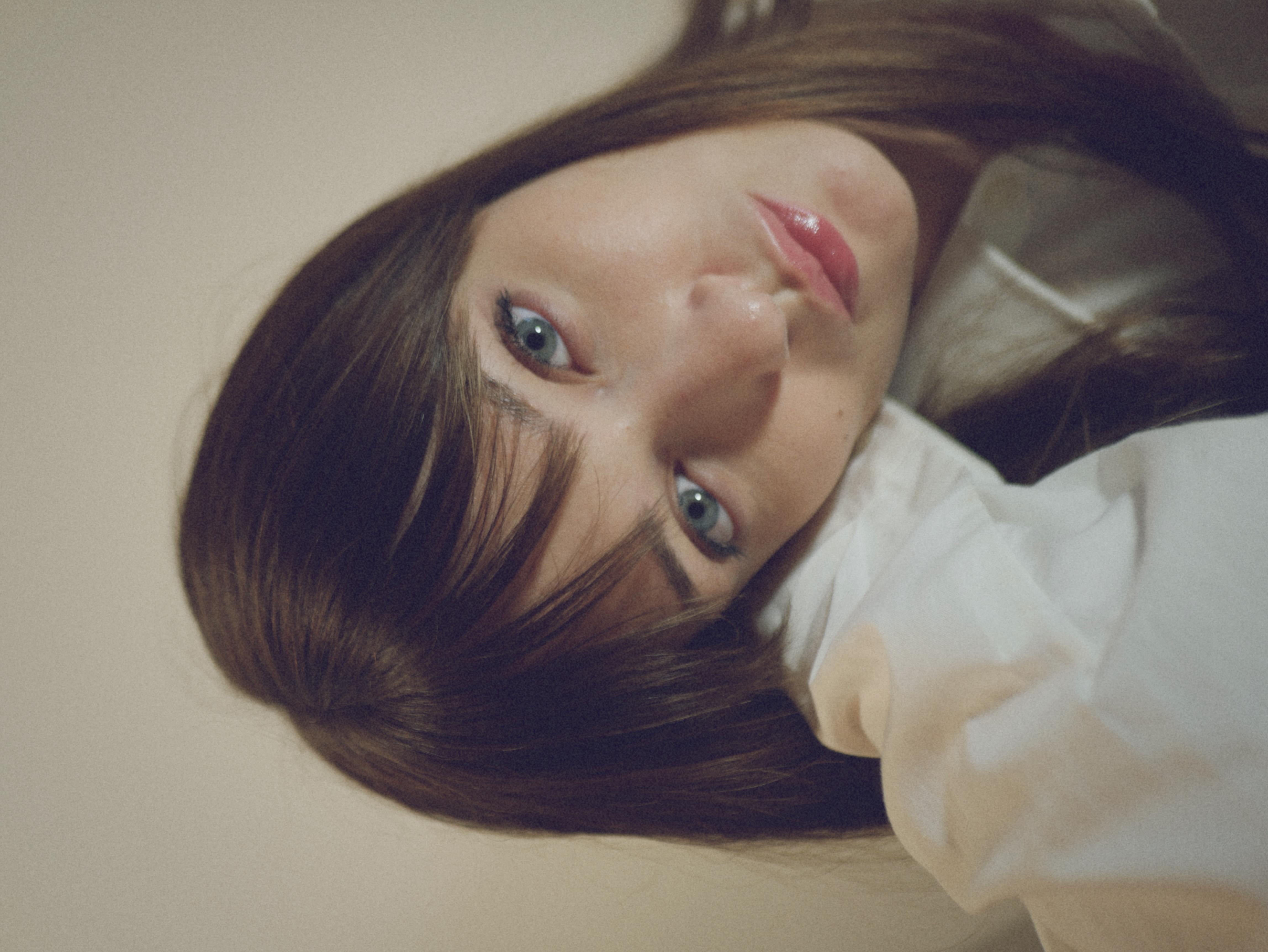 Kris Brouillette resting her head on her shoulder, looking into the camera in an oversized white shirt